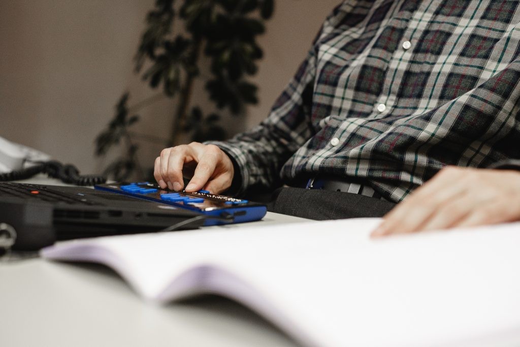 Ein Mann arbeitet mit einer Braille-Zeile an seinem Computer. Foto: Michel Arriens