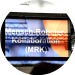 Blau-orangefarbenes Schild, auf dem "Mensch-Roboter-Kollaboration (MRK)" steht.