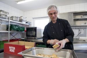 Rolf Adämmer öffnet eine neue Packung Butterkekse, um sie zu zerkleinern.