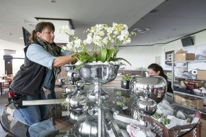 Die Inhaberin Birgit Honvehlmann steckt einen Strauß aus weißen Blumen in einem silbernen Kelch zusammen.