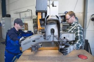 Zwei Mitarbeiter bedienen gemeinsam ein großes Industriegerät