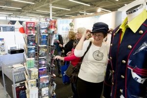 Eine Frau probiert am Stand des Second-Hand-Shops von HFR-Rümpelfix einen Hut an und freut sich.