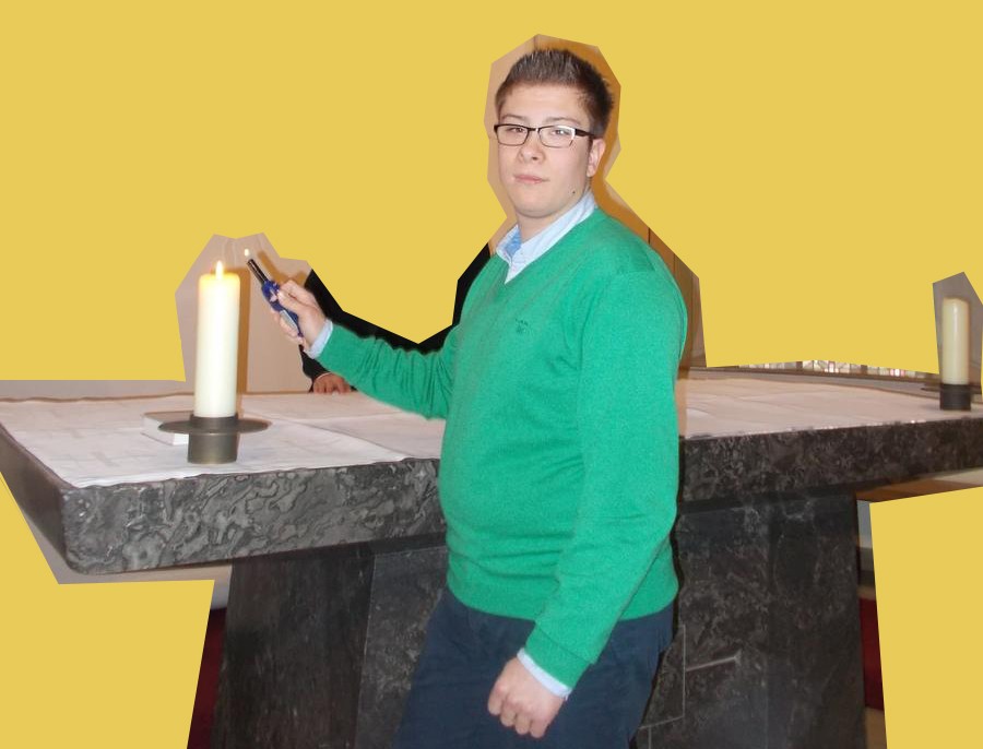 Niklas Grewing steht am Altar und zündet eine Kerze an.