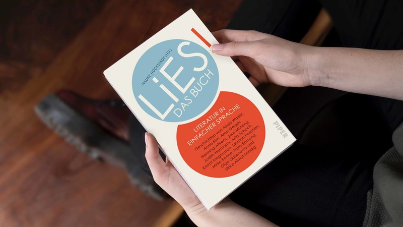 Das Buch "LiES" von oben fotografiert; eine Frau hält es in den Händen, das Gesicht der Person sieht man nicht.