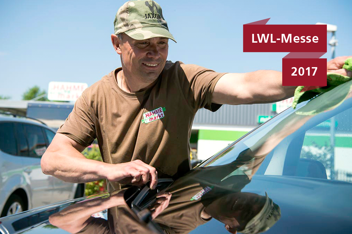 Ein Mitarbeiter des Servicehauses beim Reinigen einer Autoscheibe.