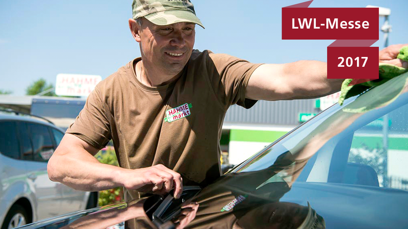 Ein Mitarbeiter des Servicehauses beim Reinigen einer Autoscheibe.