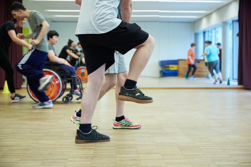 Eine Gruppe Menschen mit verschiedenen Behinderungen beim Sport in einer Turnhalle.
