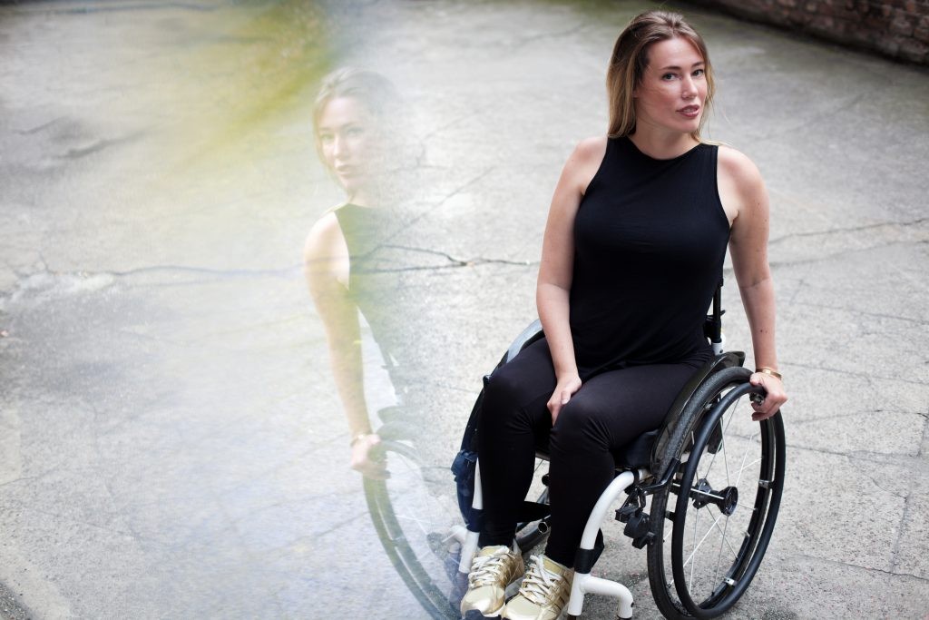 Die Autorin Laura Gehlhaar in ihrem Rollstuhl. Sie schaut in die Kamera.