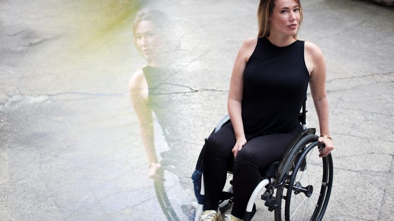 Die Autorin Laura Gehlhaar in ihrem Rollstuhl. Sie schaut in die Kamera.