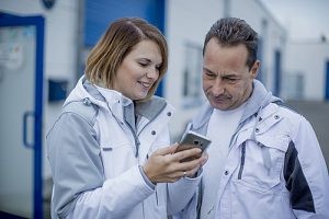 Malermeisterin Jessica Müller zeigt ihrem Mitarbeiter Ralph Müller auf dem Smartphone, was sie ihm sagen will.