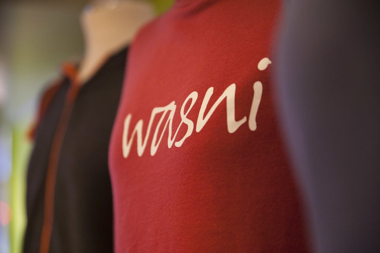 Bunte Pullis auf Schneiderpuppen, in der Bildmitte ein roter Pulli, auf dem "wasni" steht.