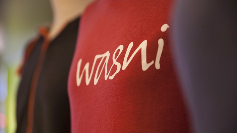 Bunte Pullis auf Schneiderpuppen, in der Bildmitte ein roter Pulli, auf dem "wasni" steht.