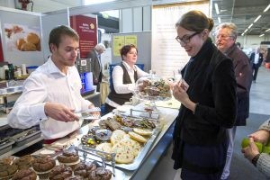 Eine Besucherin lässt sich an der Kuchentheke die Auswahl zeigen.