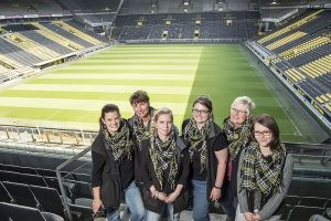 Das Team des Blumengeschäfts auf der BVB-Tribüne, im Hintergrund das noch leere Spielfeld.