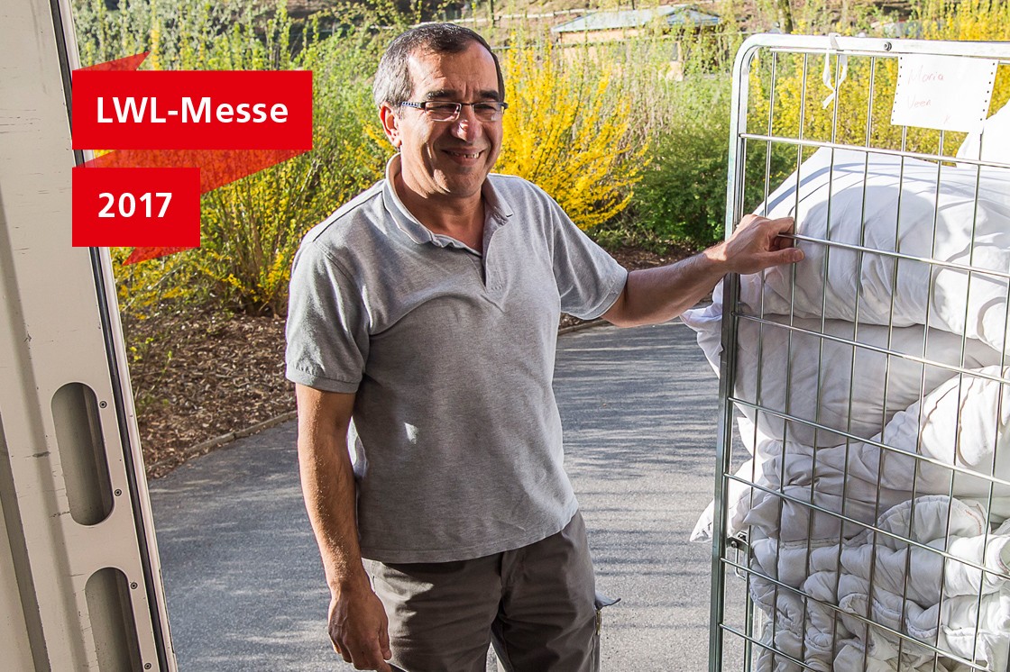 Ali Cütcü auf der Laderampe seines Lieferwagens neben einem Gitterwagen mit frischer Wäsche.