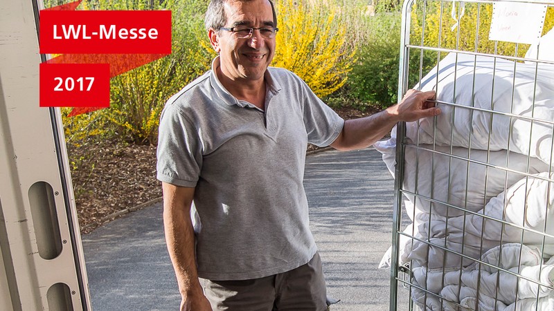 Ali Cütcü auf der Laderampe seines Lieferwagens neben einem Gitterwagen mit frischer Wäsche.