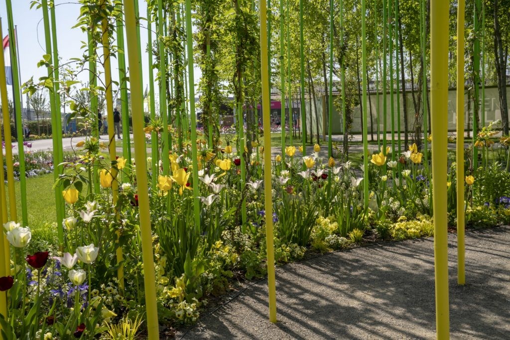 Buntes Blumenbeet aus Tulpen und anderen Blumen, dazwischen ragen lange, gelbe Stäbe auf. Foto: BUGA Heilbronn 2019 GmbH