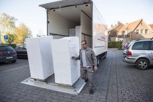 Ali Cütcü neben zwei weißen Wäschecontainern, die er gerade ausgeladen hat.