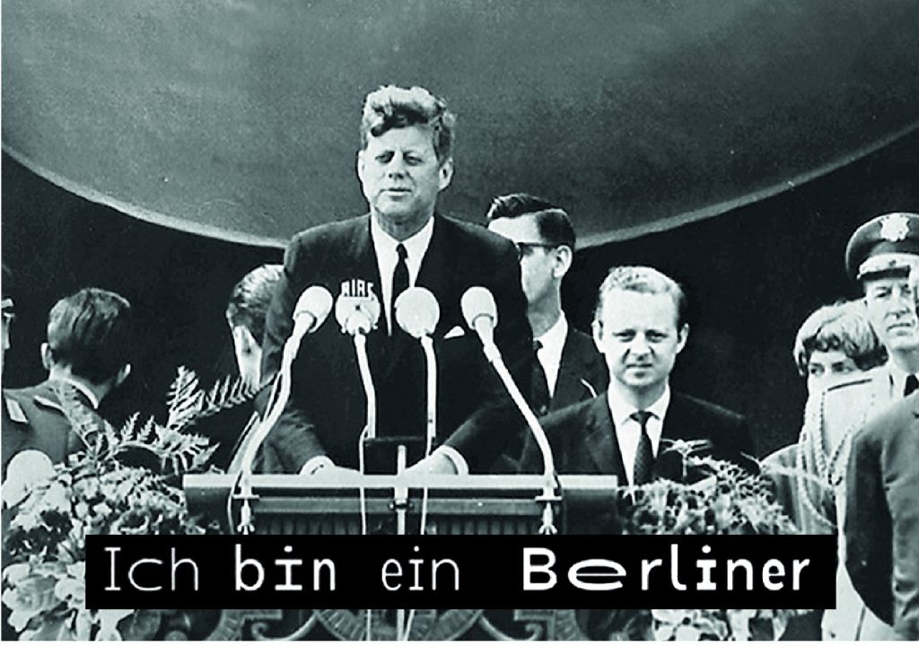 Der ehemalige Präsident der USA, Kennedy, steht an einem Rednerpult. Darunter ist in WaveFont-Untertiteln der Satz "Ich bin ein Berliner" dargestellt.