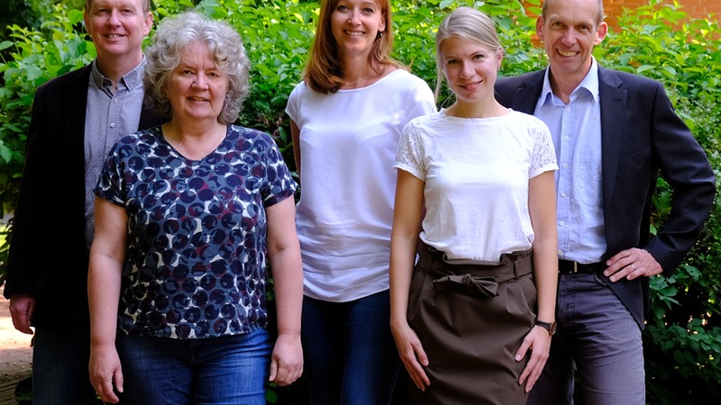 Das Team der Fachstelle Behinderte Menschen im Beruf im Kreis Herford bei schönem Wetter vor einer grünen Hecke fotografiert.